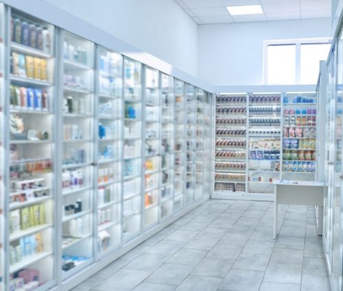 Drugstore furnished with numerous glass display cabinets filled with different pharmaceutical drugs and beauty products