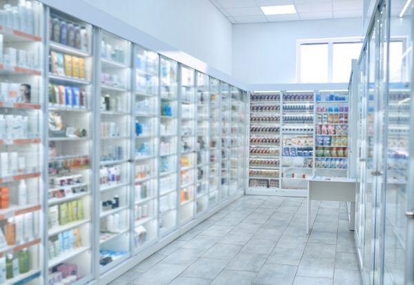 Drugstore furnished with numerous glass display cabinets filled with different pharmaceutical drugs and beauty products